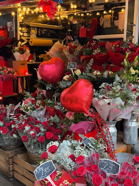 A vibrant display of fresh floral arrangements at floristleytonstone.co.uk under warm ambient lighting, featuring predominantly red and white roses, complemented by sprigs of eucalyptus and other gree